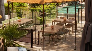An outdoor seating area with tables and chairs, a large umbrella, and a pool in the background. - Victoria Boutique Hôtel (Saint-Paul-Trois-Chateaux)