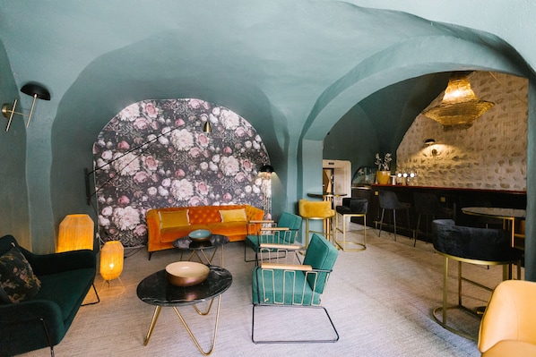 A cozy interior with a sofa, chairs, a round table, and a bar area.