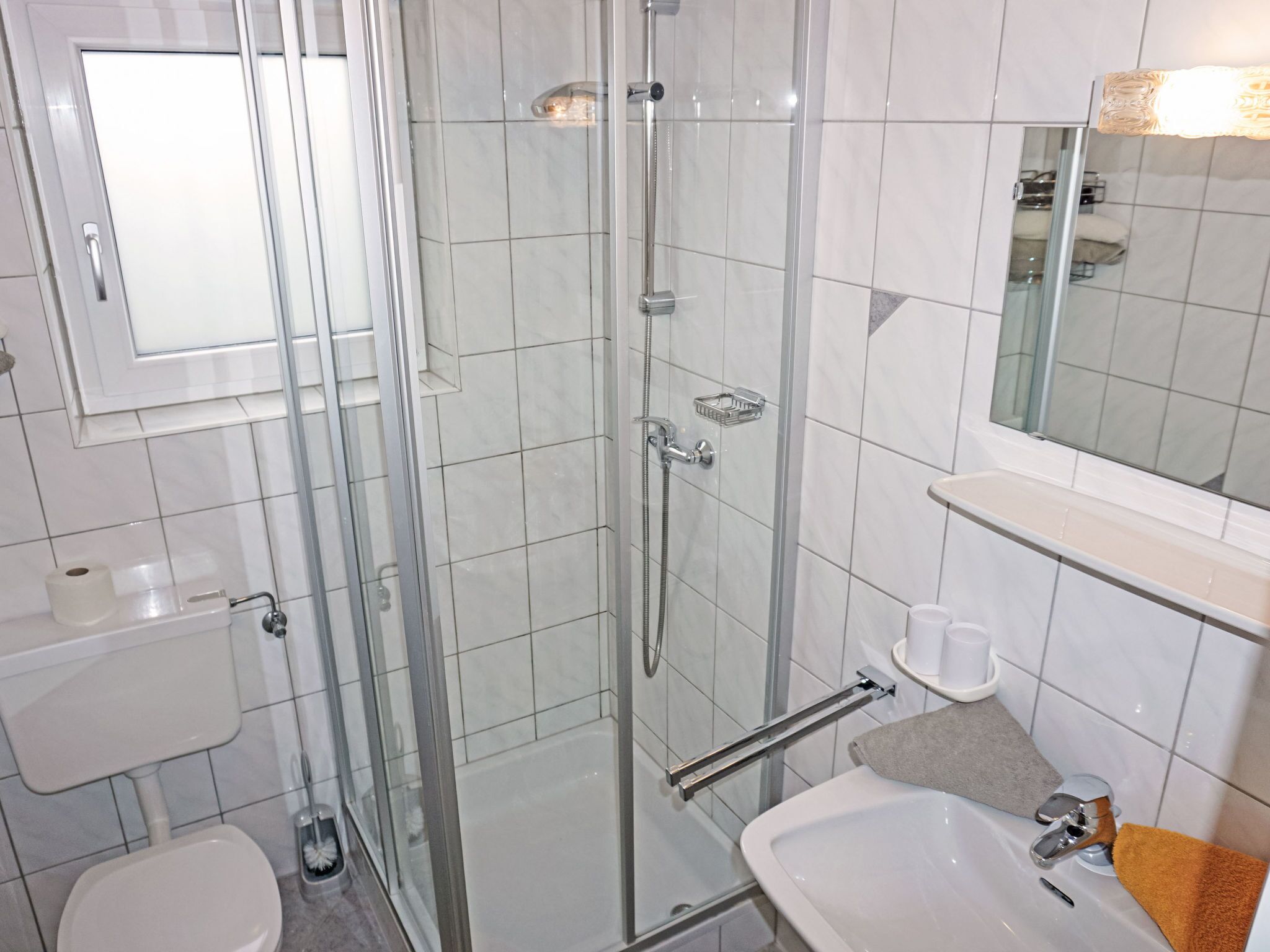 Une salle de bain moderne dotée d’une douche à parois de verre, de toilettes, d’un lavabo et d’un miroir.