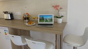 Une cuisine équipée d’un ordinateur portable, d’un grille-pain, d’un panier de fruits et d’une plante en pot.