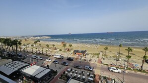 Blick auf einen Strand mit einem KFC-Restaurant, Palmen und einem Yachthafen im Hintergrund.