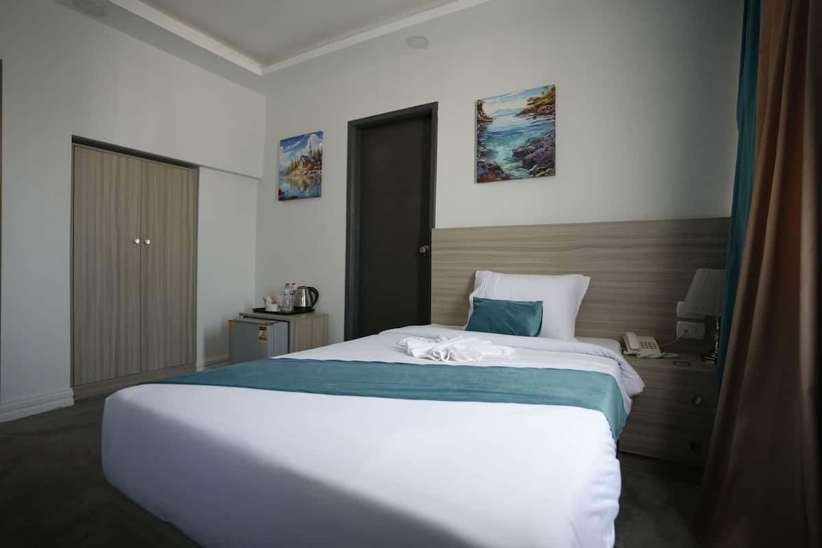 Una habitación de hotel con una cama, un escritorio, un armario y dos cuadros en la pared.
