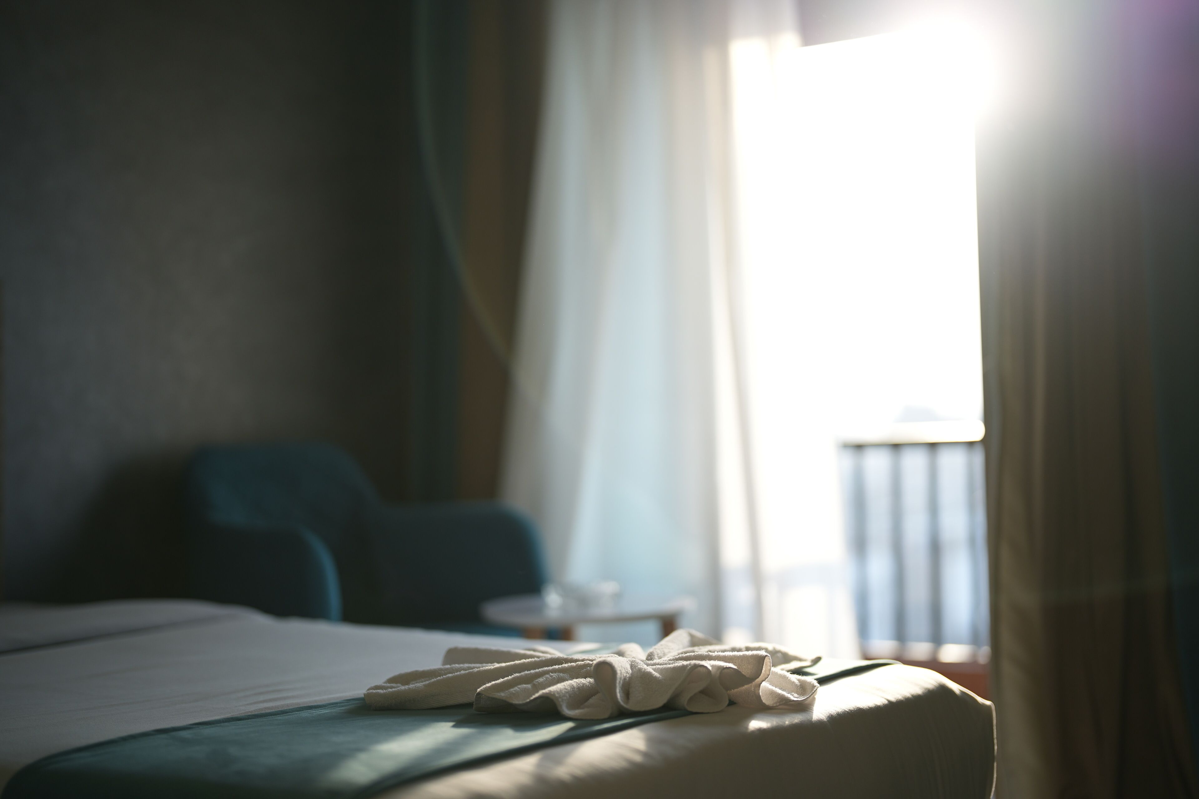 Une chambre d’hôtel avec un lit bien fait, une petite table ronde et une vue sur l’extérieur par une fenêtre.