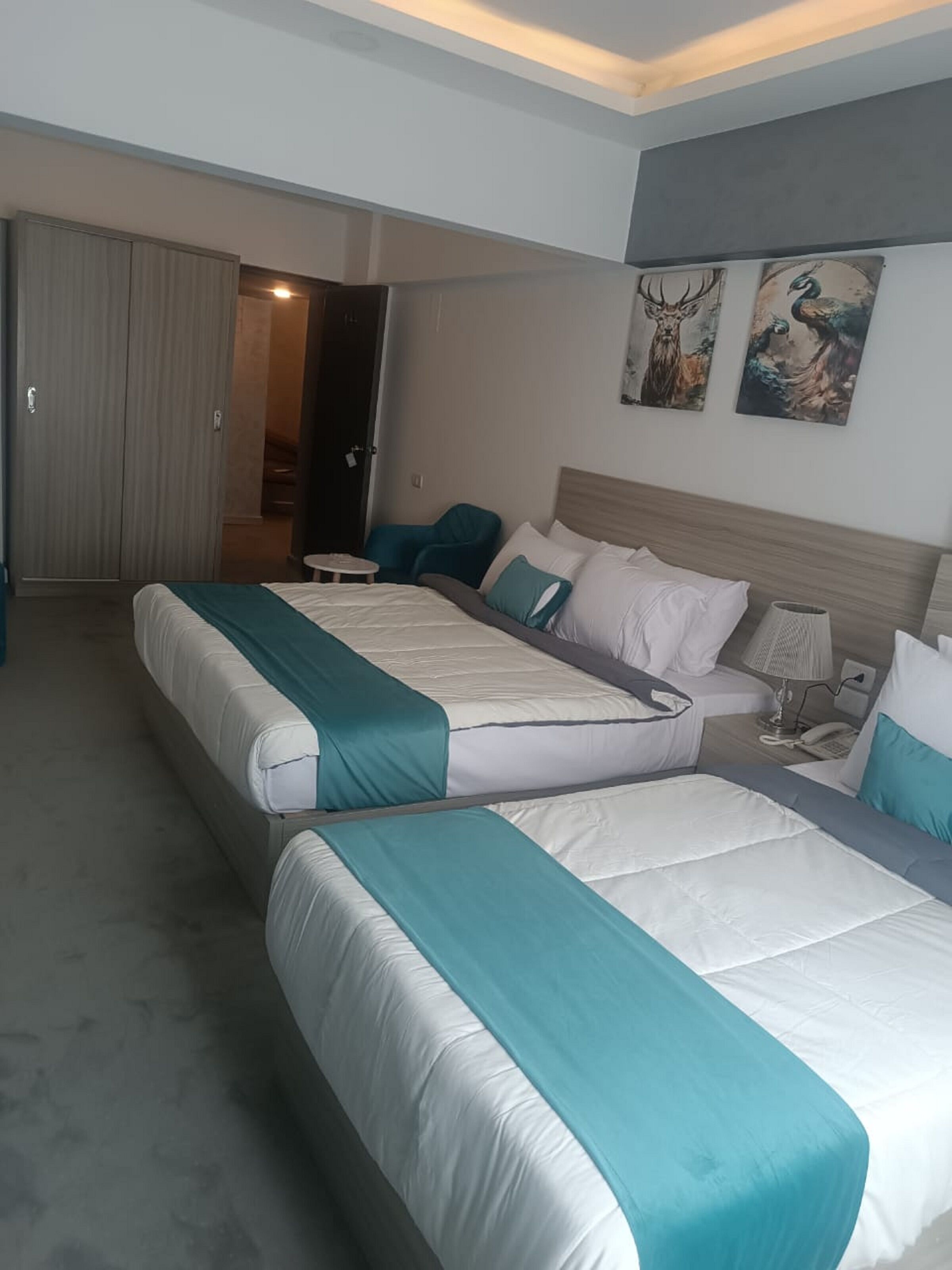 A modern hotel room with a large bed, a bedside table, a lamp, and artwork on the wall.
