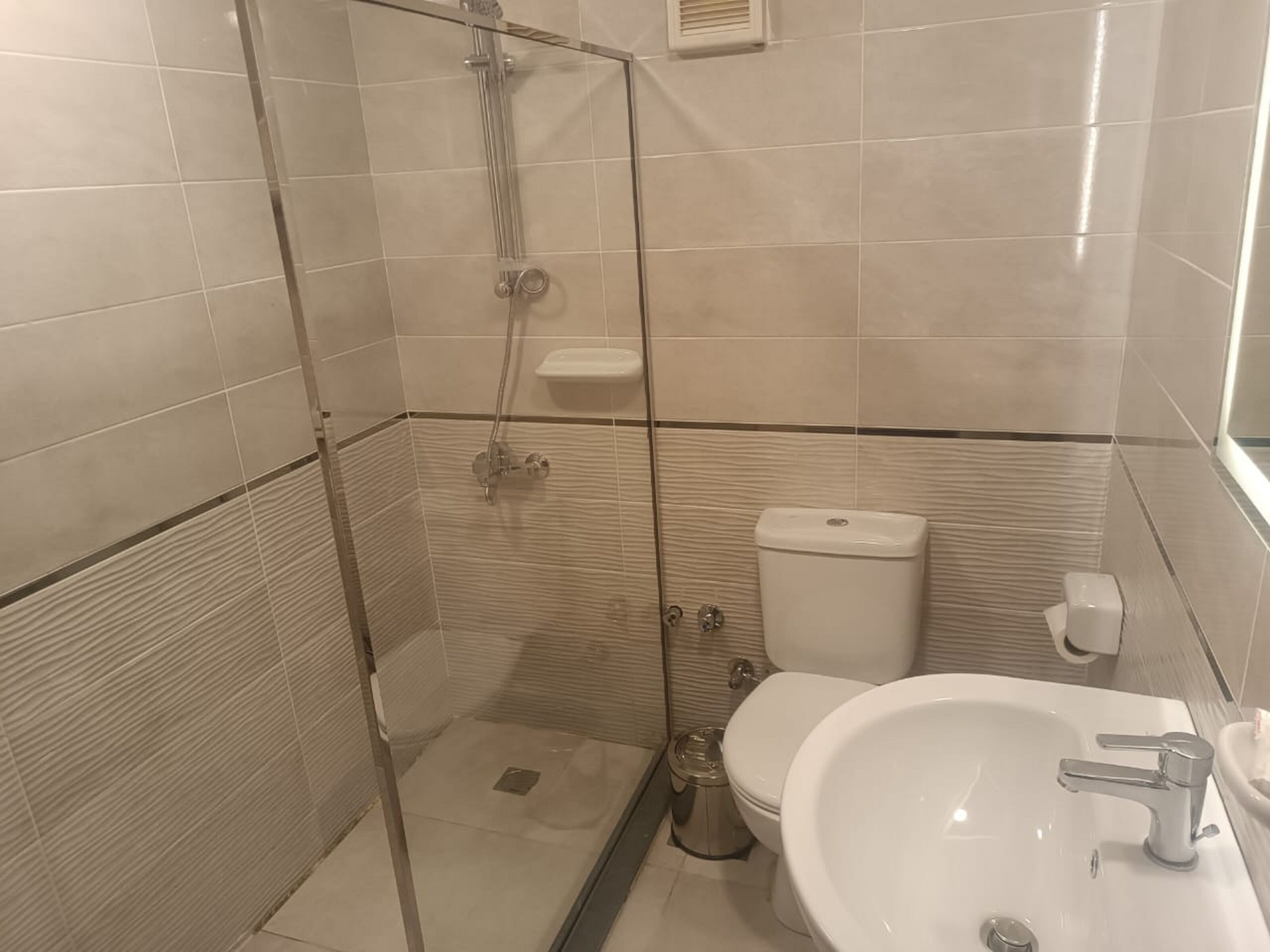 A bathroom with a glass-enclosed shower, a toilet, and a sink.