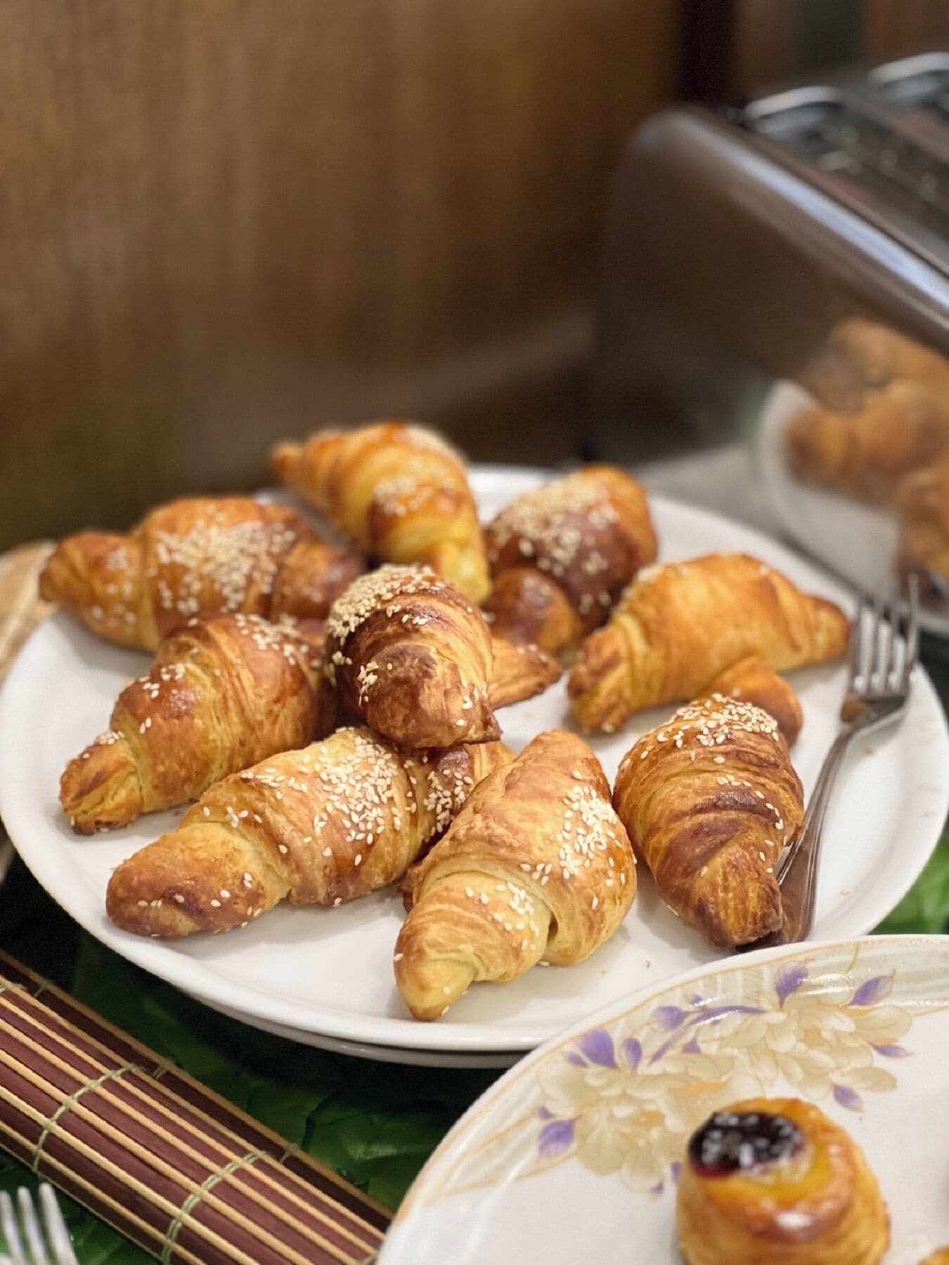 A plate of assorted pastries, including croissants and a pastry with a berry compote, on a floral-patterned plate.