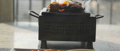 A portable grill with food on a balcony.