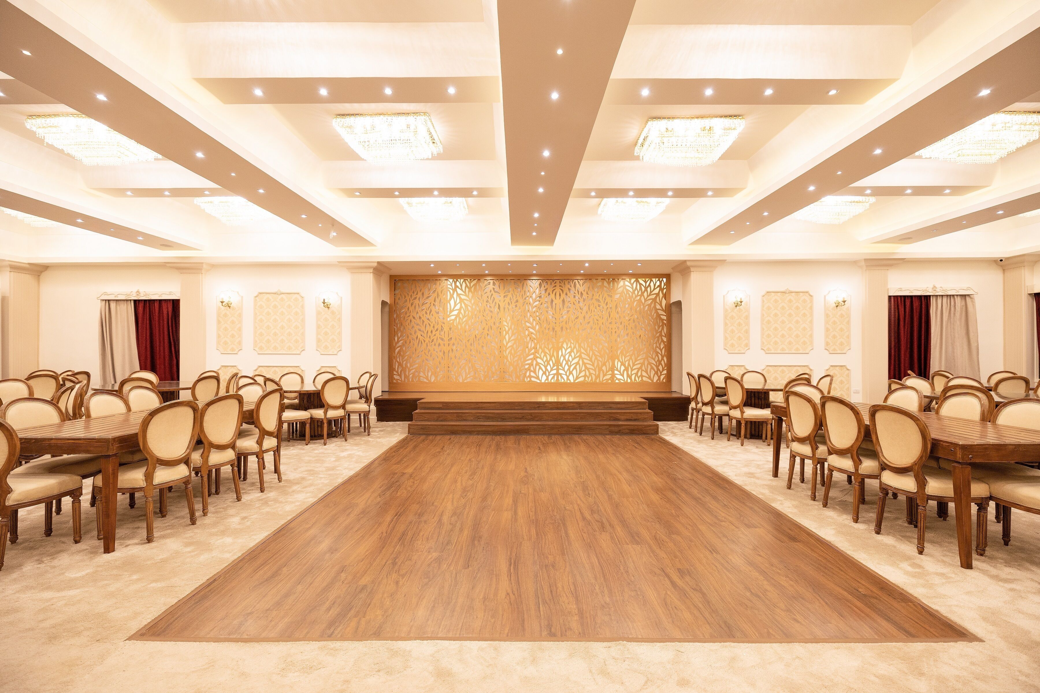 A large conference room with a long wooden table, multiple chairs, and a stage with a decorative backdrop.