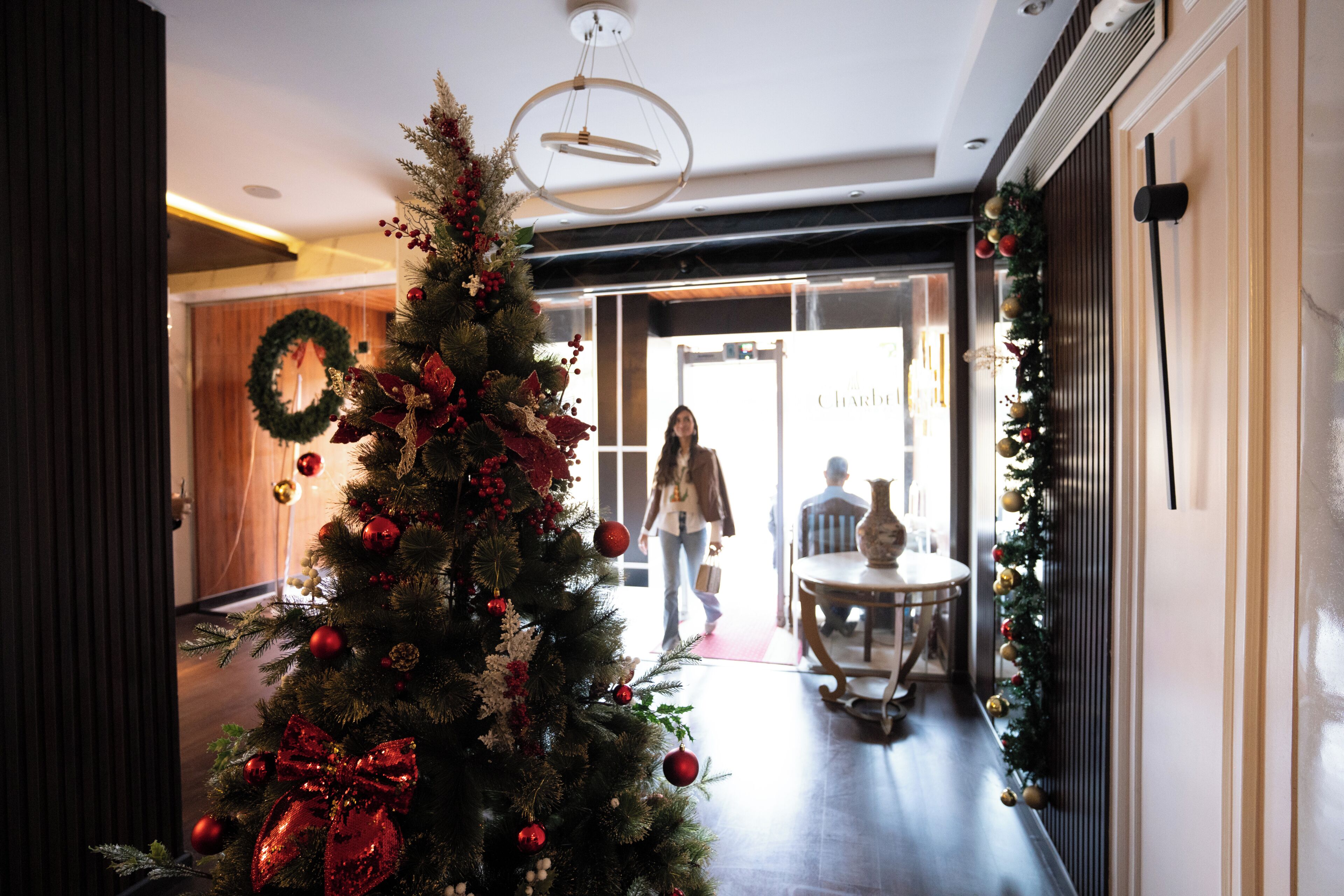 A Christmas tree with ornaments and a bow, a hallway with a door, and a table with chairs.