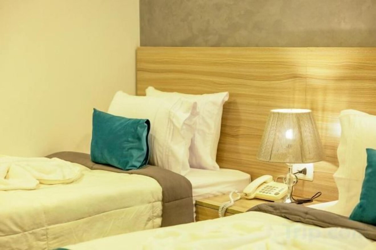 A hotel room with two beds, a bedside lamp, a telephone, and a wooden headboard.