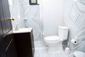 Un baño moderno con un mueble de tocador de madera oscura, un lavamanos blanco y un inodoro.