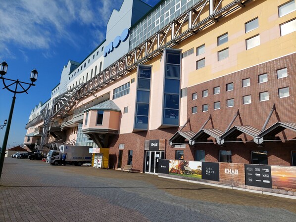 A modern building with a unique architectural design, featuring a mix of brick and glass facades, and a prominent signboard with various advertisements. - Smile Hotel Kushiro (Kushiro)