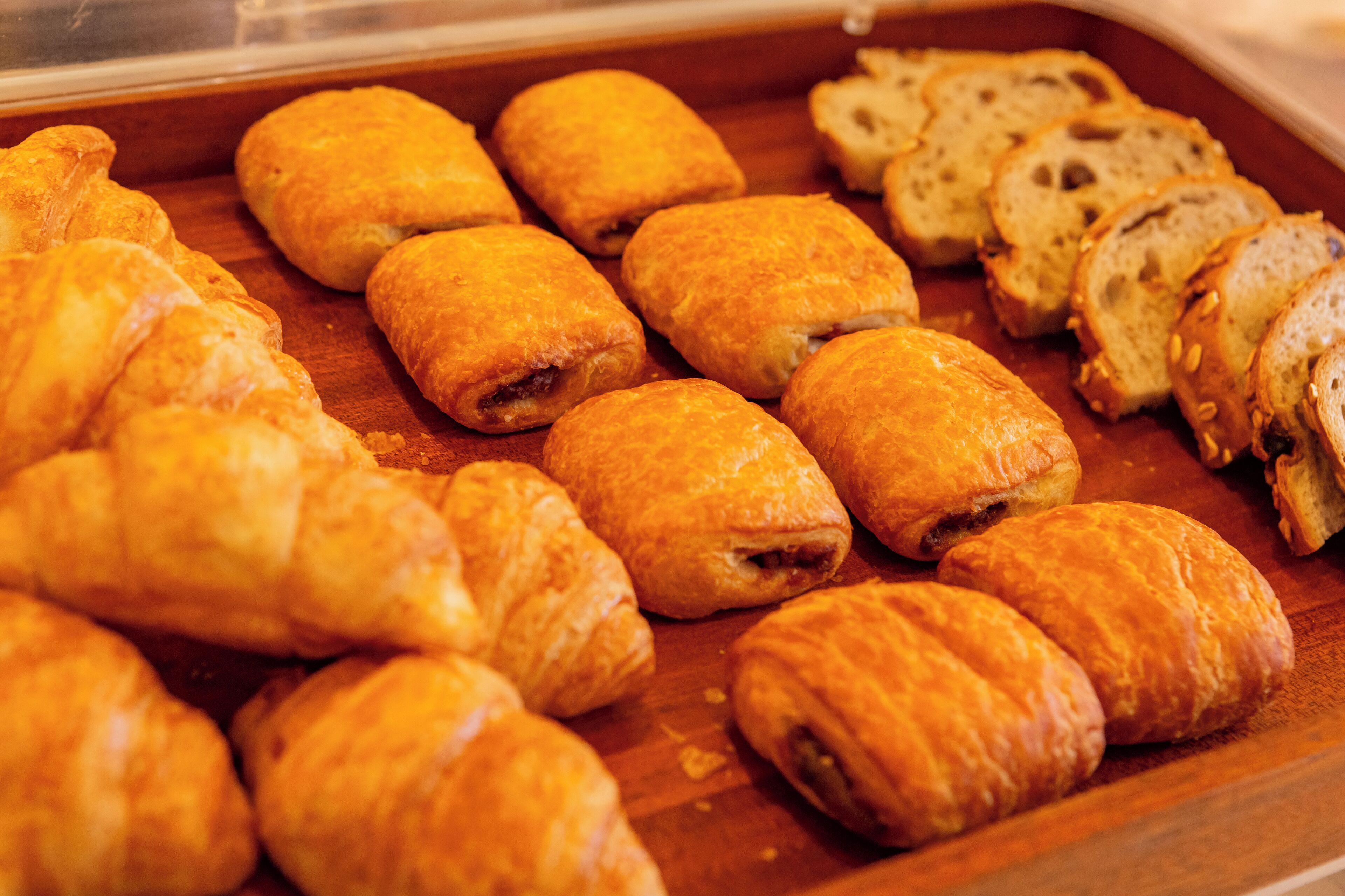 A variety of pastries, including croissants and bread, displayed on a wooden surface.