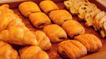 A variety of pastries, including croissants and bread, displayed on a wooden surface.