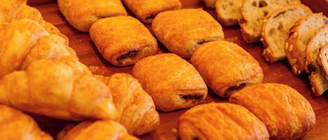 Diversas opciones de pastelería, incluyendo croissants y pan, sobre una superficie de madera.