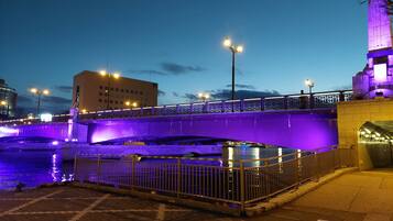 Un puente con iluminación púrpura, una estatua y un edificio con una torre.