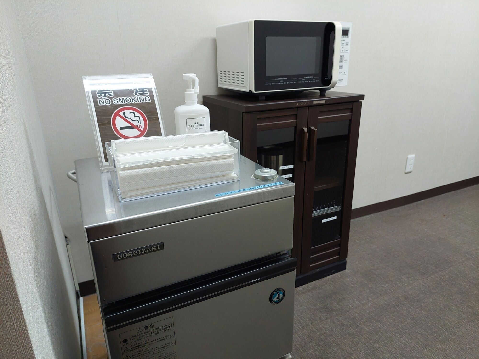 Una sala visite medica con un monitor digitale, un misuratore di pressione e un cartello che vieta di fumare.