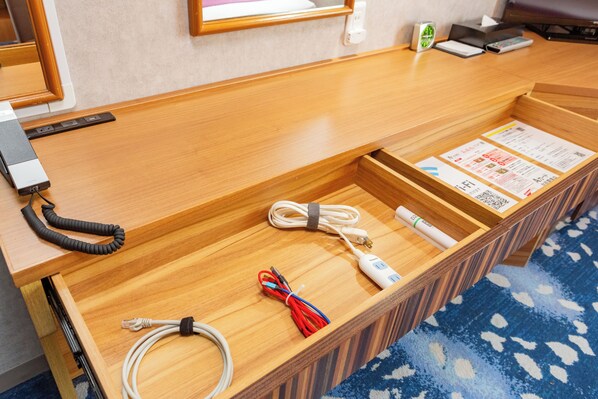 A wooden reception desk with a blue patterned carpet, a white power strip, and various cables. - Smile Hotel Kushiro (Kushiro)
