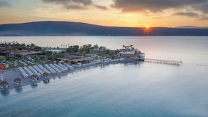Un complejo turístico costero con muelle, tumbonas y vistas al atardecer sobre el agua.