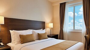 A hotel room with a large bed, two bedside tables, a nightstand, a chair, and a window with curtains. - Hotel Sunlight Inn (New Delhi)