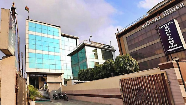 A modern building with a glass facade and a sign for 'VIRASAT HOUSE HOTEL SUNLIGHT INN'. - Hotel Sunlight Inn (New Delhi)