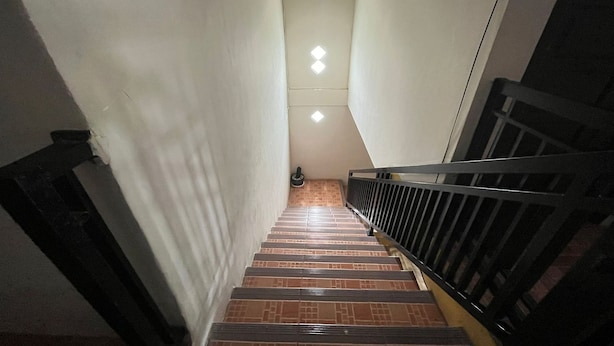 A staircase with a black railing, white walls, and a tiled floor.