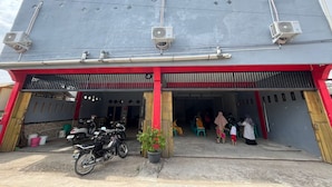 A building with a red and grey facade, air conditioning units, and a motorcycle parked in front.