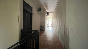 A corridor with a tiled floor, a black door, and a small potted plant.