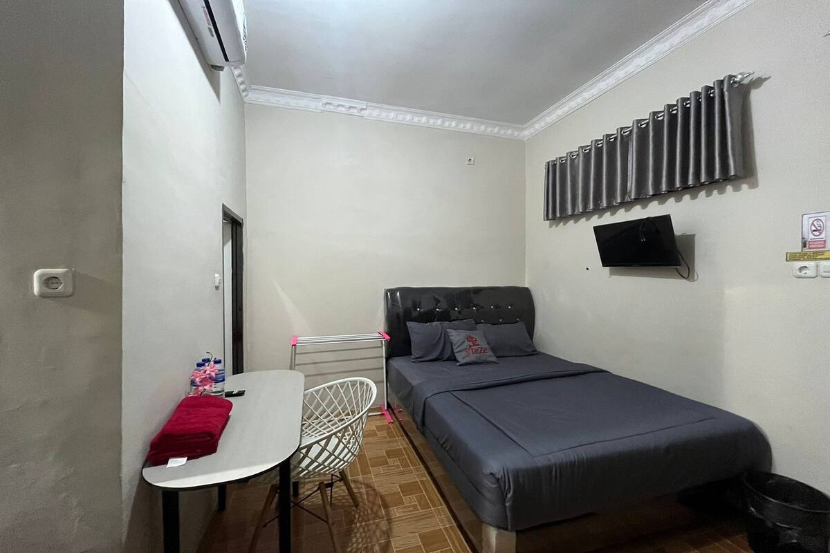 A small, compact room with a bed, a table, and a chair.
