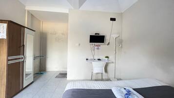 A hotel room with a bed, a desk with a computer, a TV, and a wardrobe.