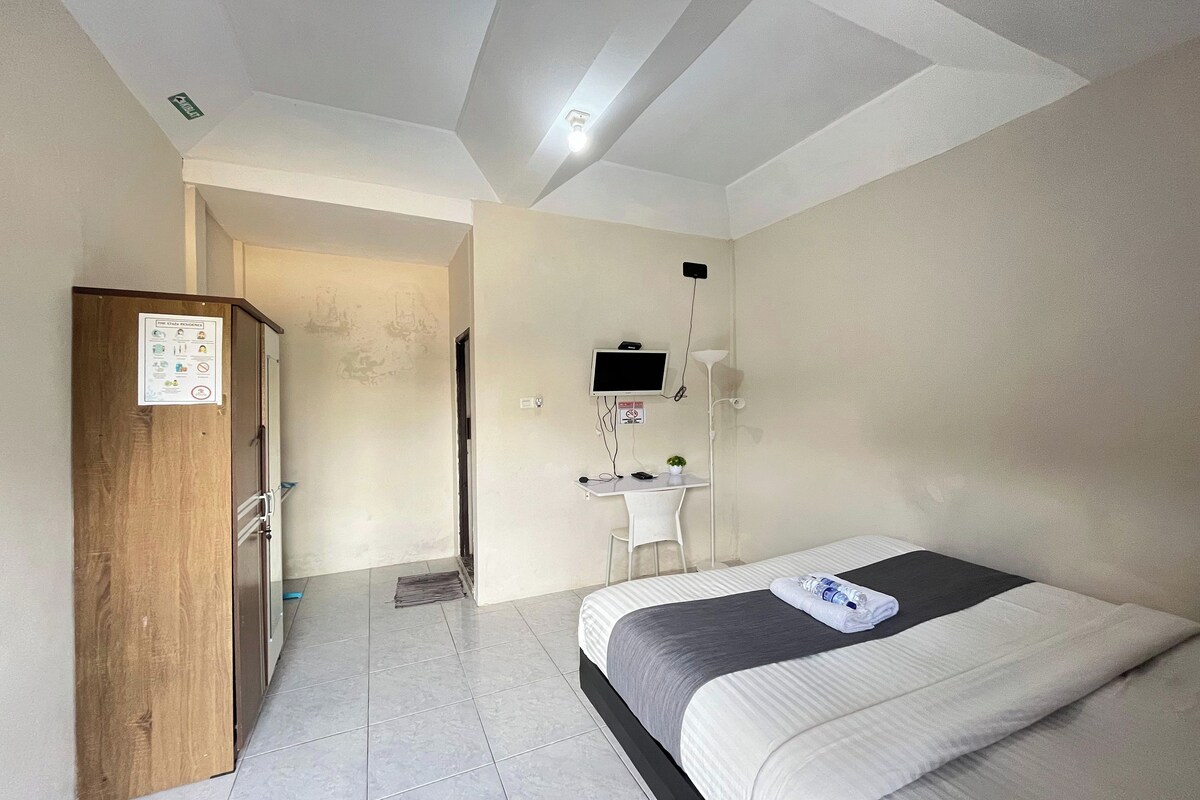Ein Hotelzimmer mit Bett, Schreibtisch, Stuhl, Fernseher und einem Holzschrank.