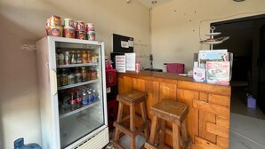 A kitchenette with a refrigerator stocked with beverages, a microwave, and a wooden bar area with stools. - Steze Guesthouse Syariah Telanaipura (Jambi)
