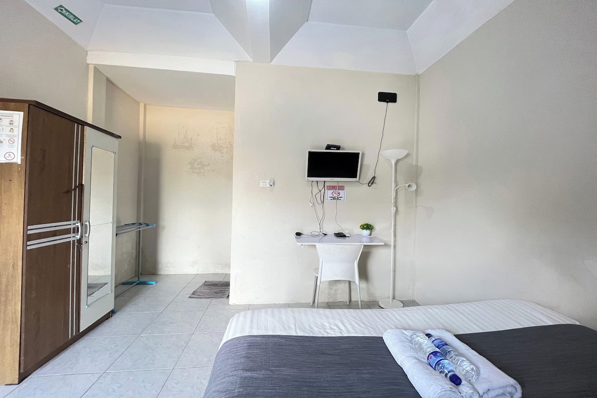 Ein Hotelzimmer mit Bett, Schreibtisch mit Computer, Fernseher und Kleiderschrank.