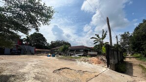 A construction site with a concrete road, a metal fence, and a building with a red roof. - Steze Guesthouse Syariah Telanaipura (Jambi)