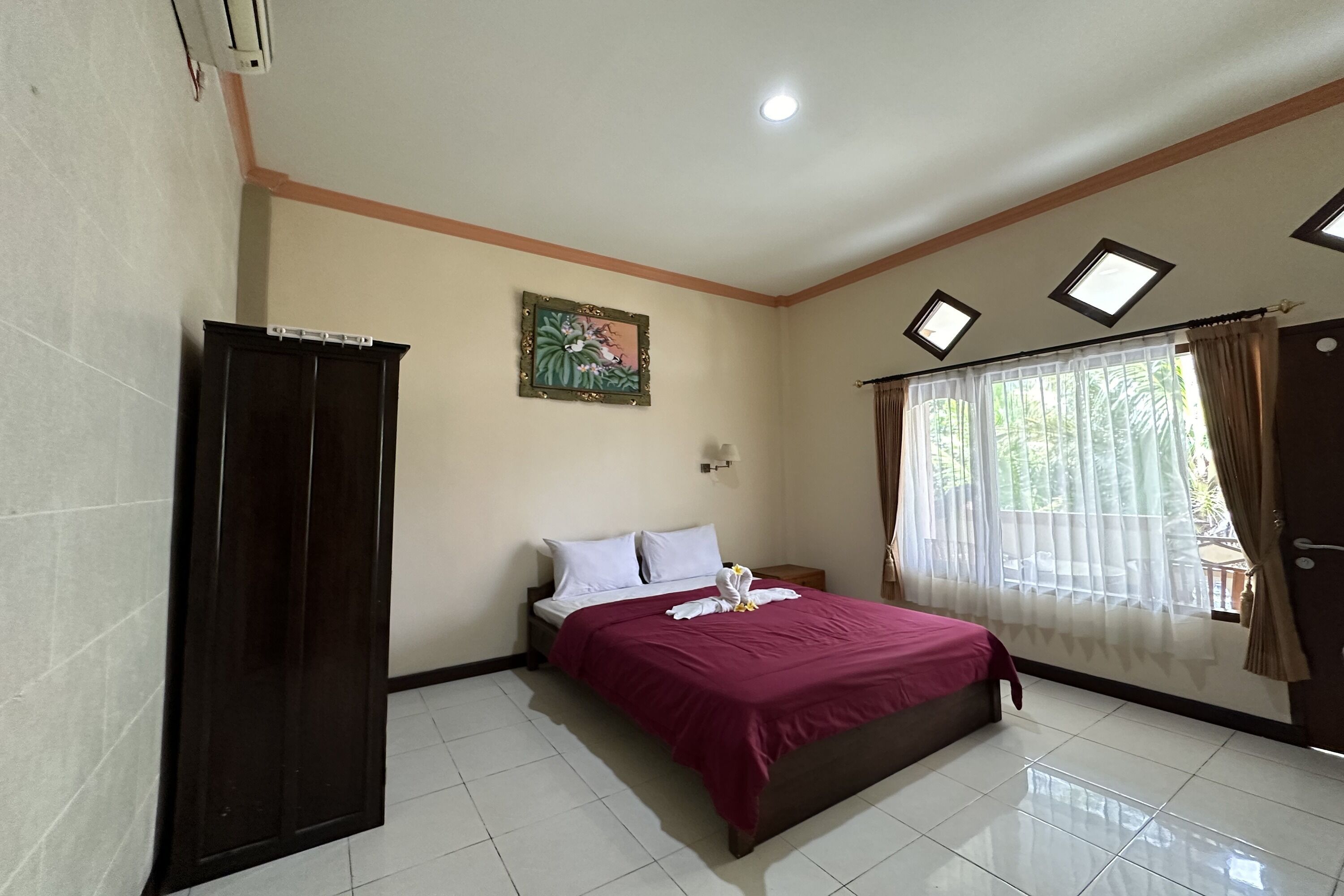 A bedroom with a bed, a wardrobe, a painting, a window with curtains, and a ceiling light.