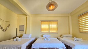 A hotel room with three single beds, a large window with blinds, a hanging light fixture, and a wall decoration. - Surfers Point Deck An'nex (San Juan)
