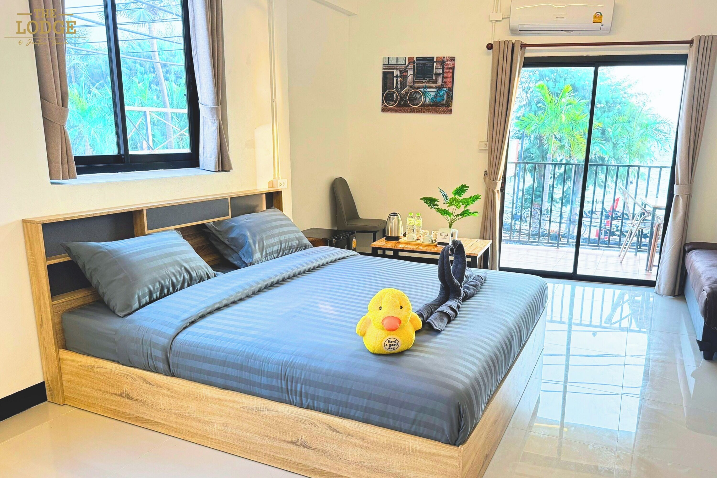 A bedroom with a bed, a chair, a small table with a plant, and a window with curtains.