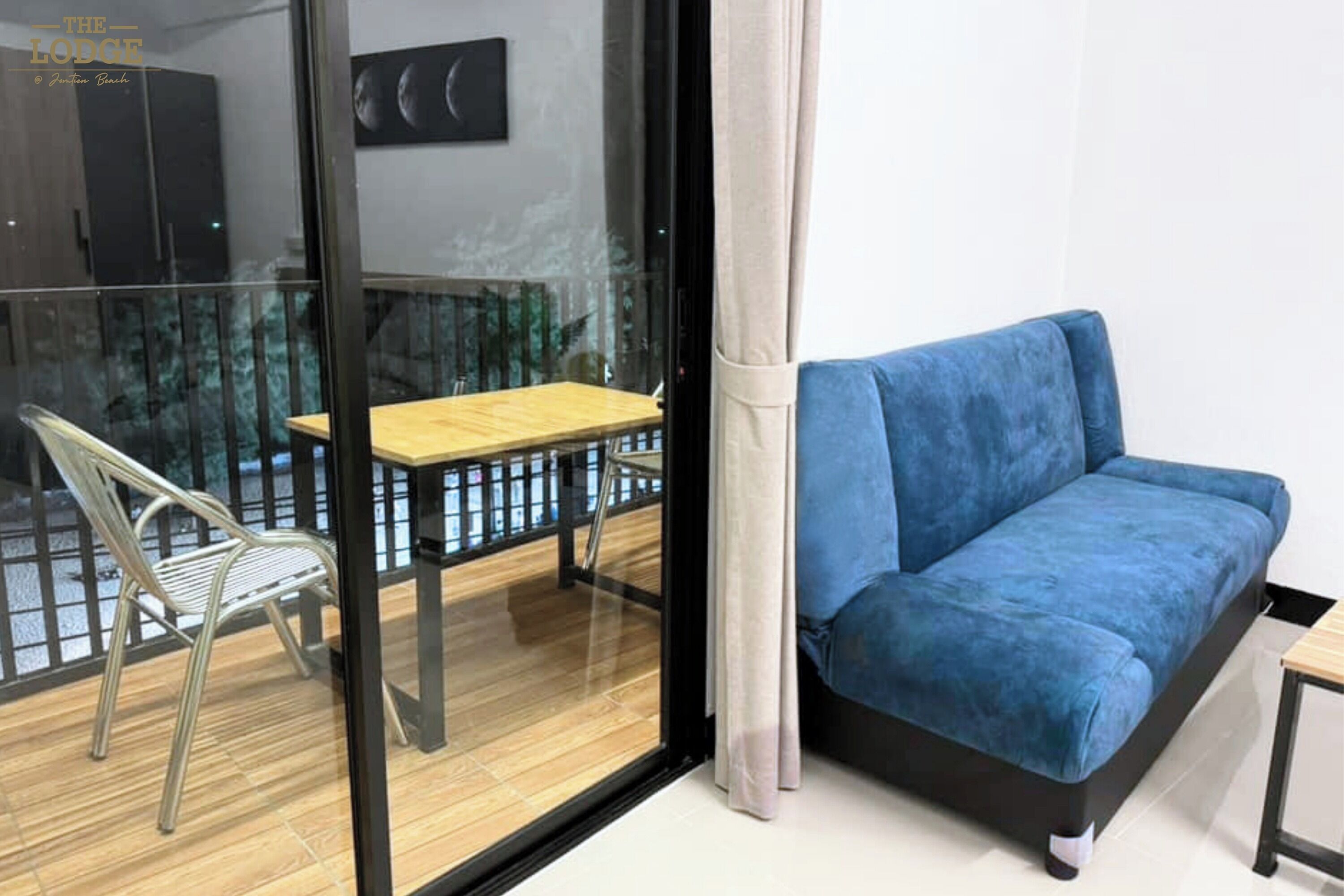 Um quarto moderno com um sofá azul, uma pequena mesa de madeira e uma cadeira de metal.