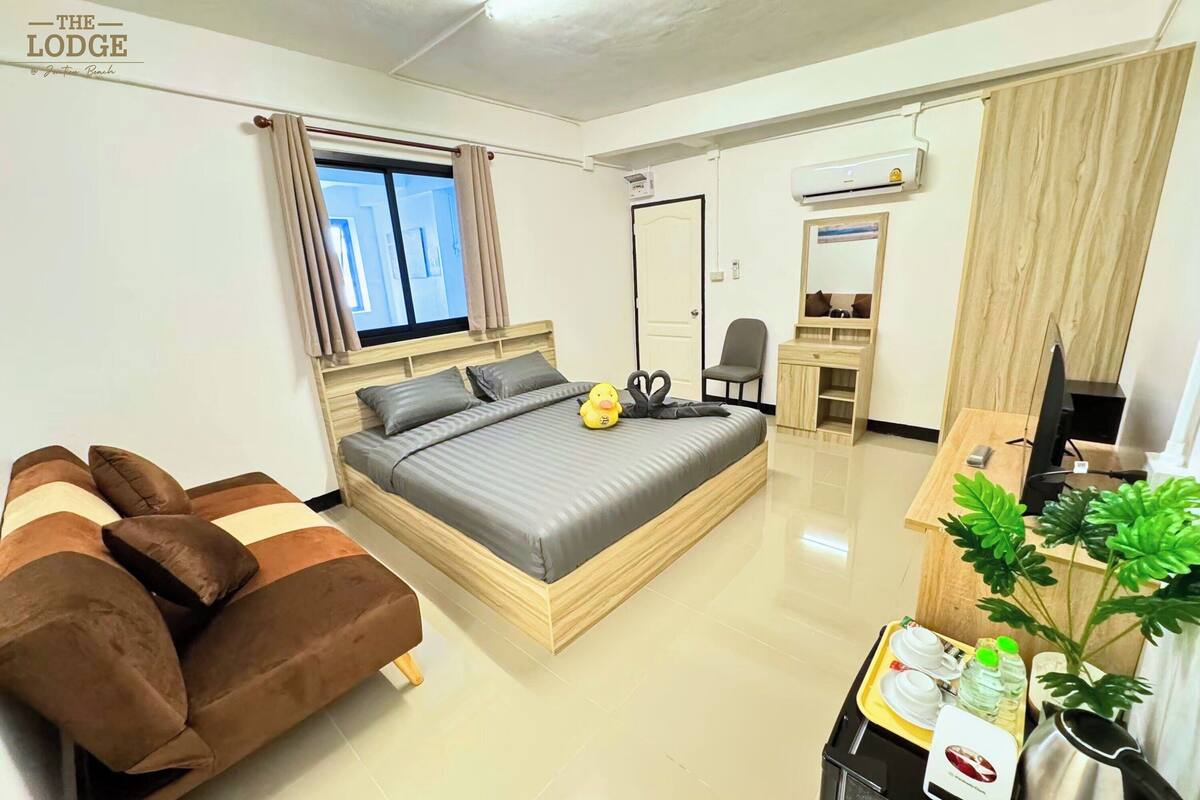 Une chambre d’hôtel moderne avec un grand lit, un canapé, un bureau et une plante.