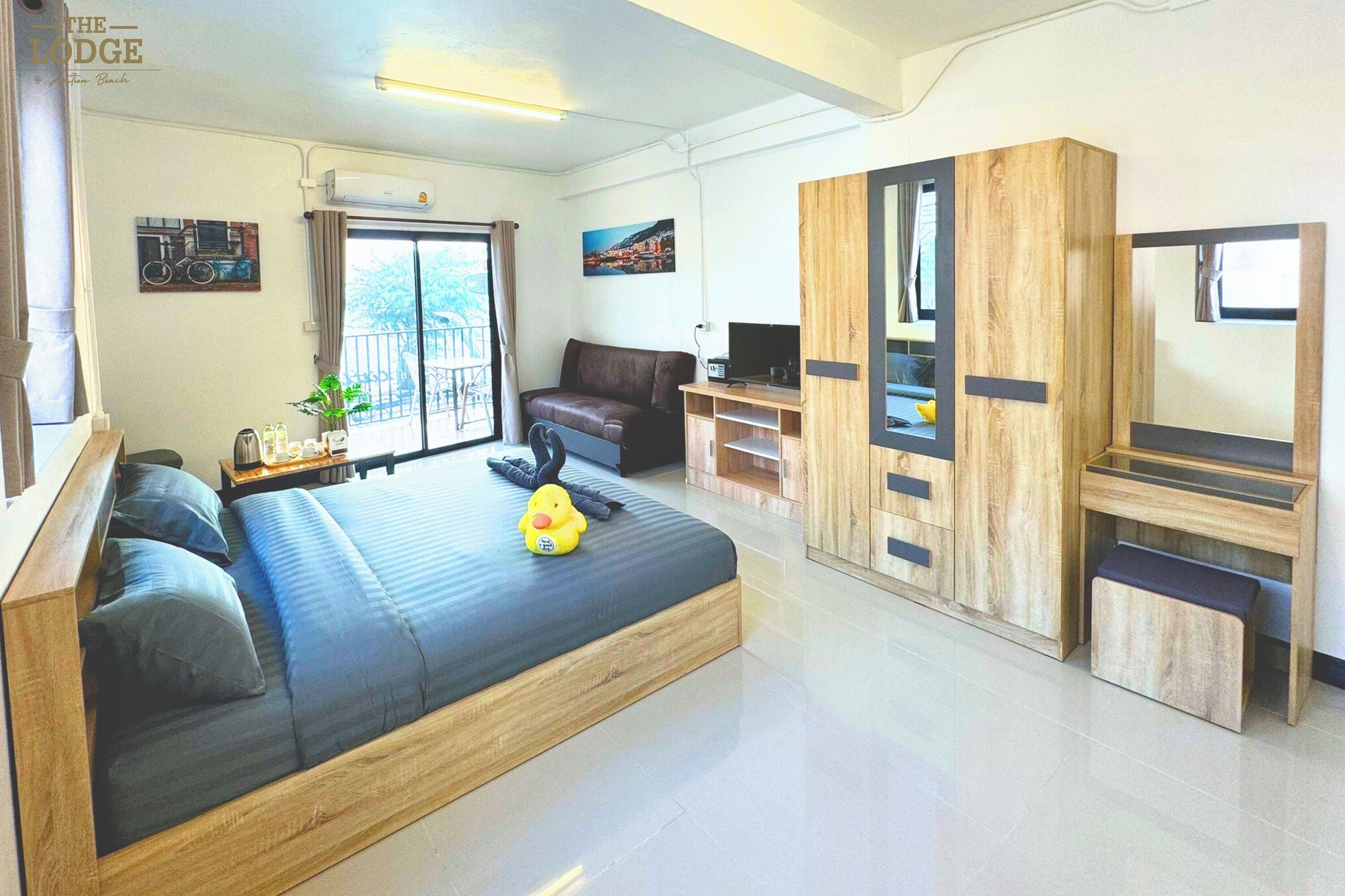 A modern hotel room with a large bed, a sofa, a desk, and a wardrobe.