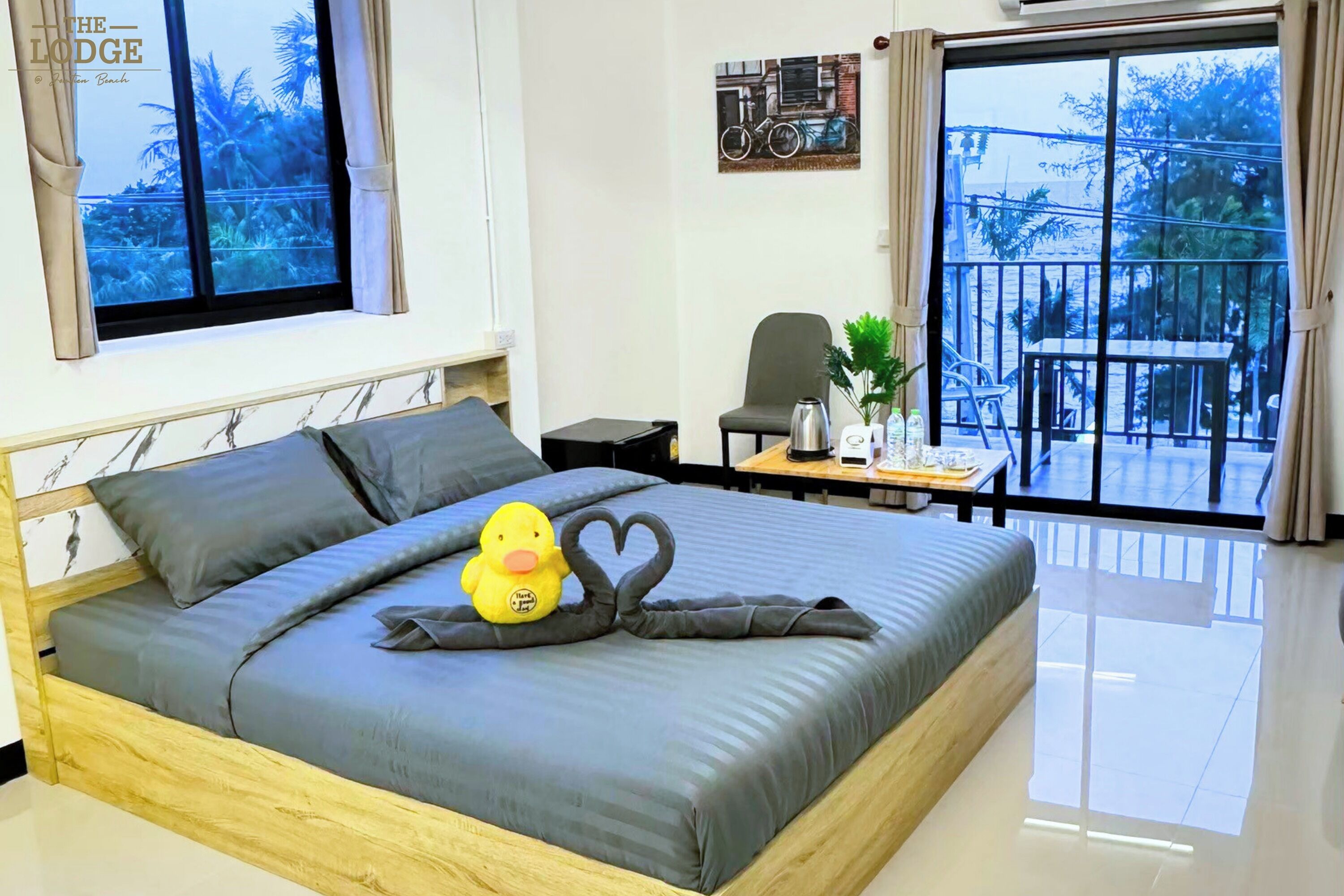 Un dormitorio con cama, ventana, una silla, una mesa y un balcón.