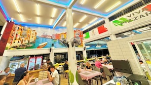 A restaurant interior with a mural, tables, chairs, and a Coca-Cola refrigerator. - The Lodge Jomtien 7 (Pattaya)