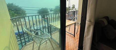 En balkon med udsigt over stranden, et bord, stole og en sofa.