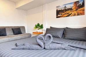 Et hotelværelse med en seng, en sofa, et maleri og en potteplante.