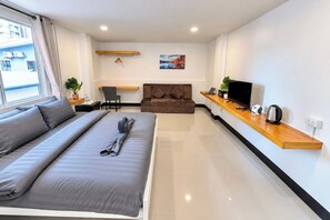 Ein modernes Hotelzimmer mit Bett, Sofa, Fernseher und einem kleinen Tisch.