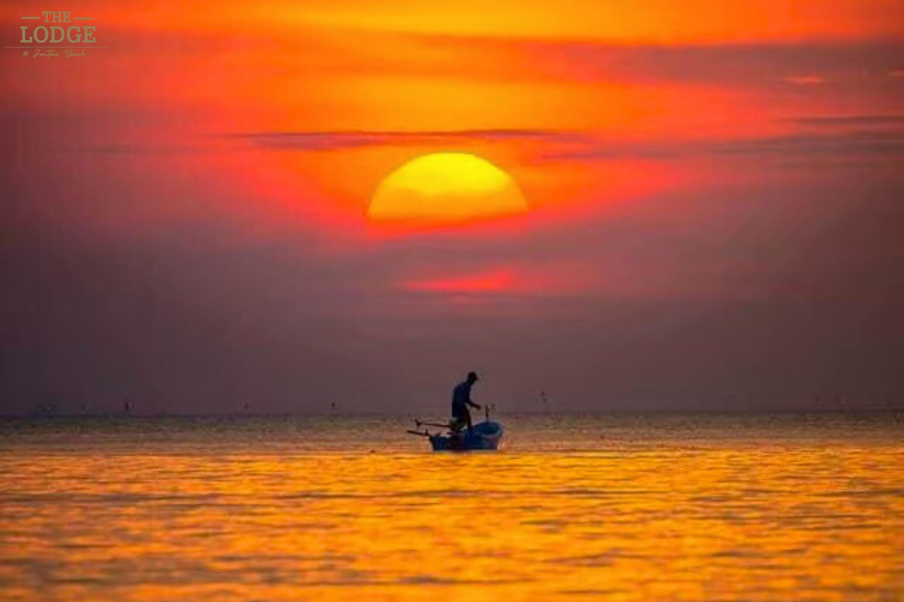 A sunset over a calm sea with a single boat and a person on it.
