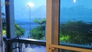 Un balcon avec une table et des chaises, offrant une vue panoramique sur la mer et la verdure.