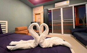 Ein Hotelzimmer mit einem Bett, einem Sofa, einem Sessel und einer großen Schiebeglasdoor zum Außenbereich.