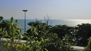 Une vue sur la mer depuis un balcon, avec une végétation luxuriante et un lampadaire.