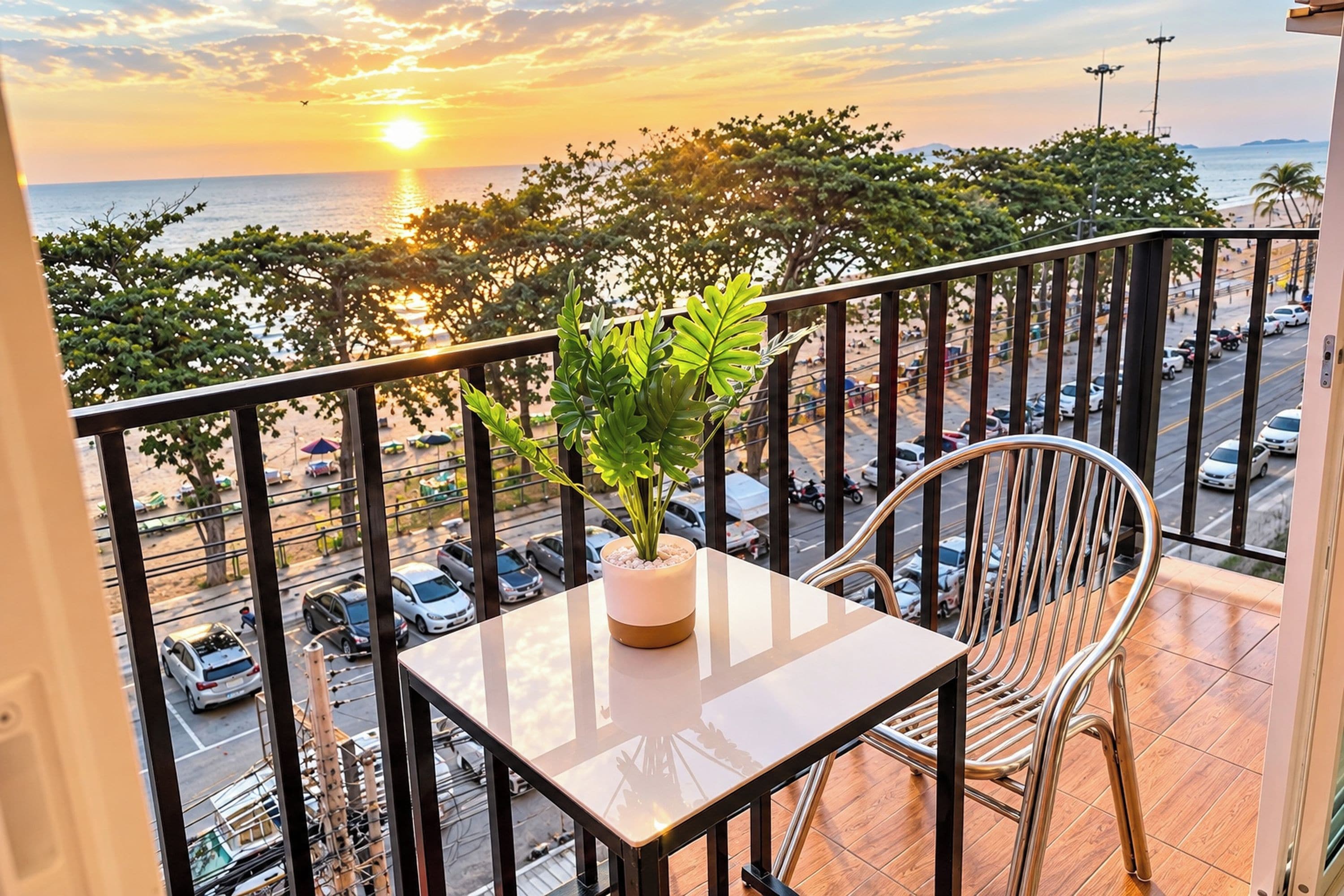 Ein Balkon mit Blick auf den Sonnenuntergang über dem Meer, einer Topfpflanze und einem Tisch mit einem Stuhl.